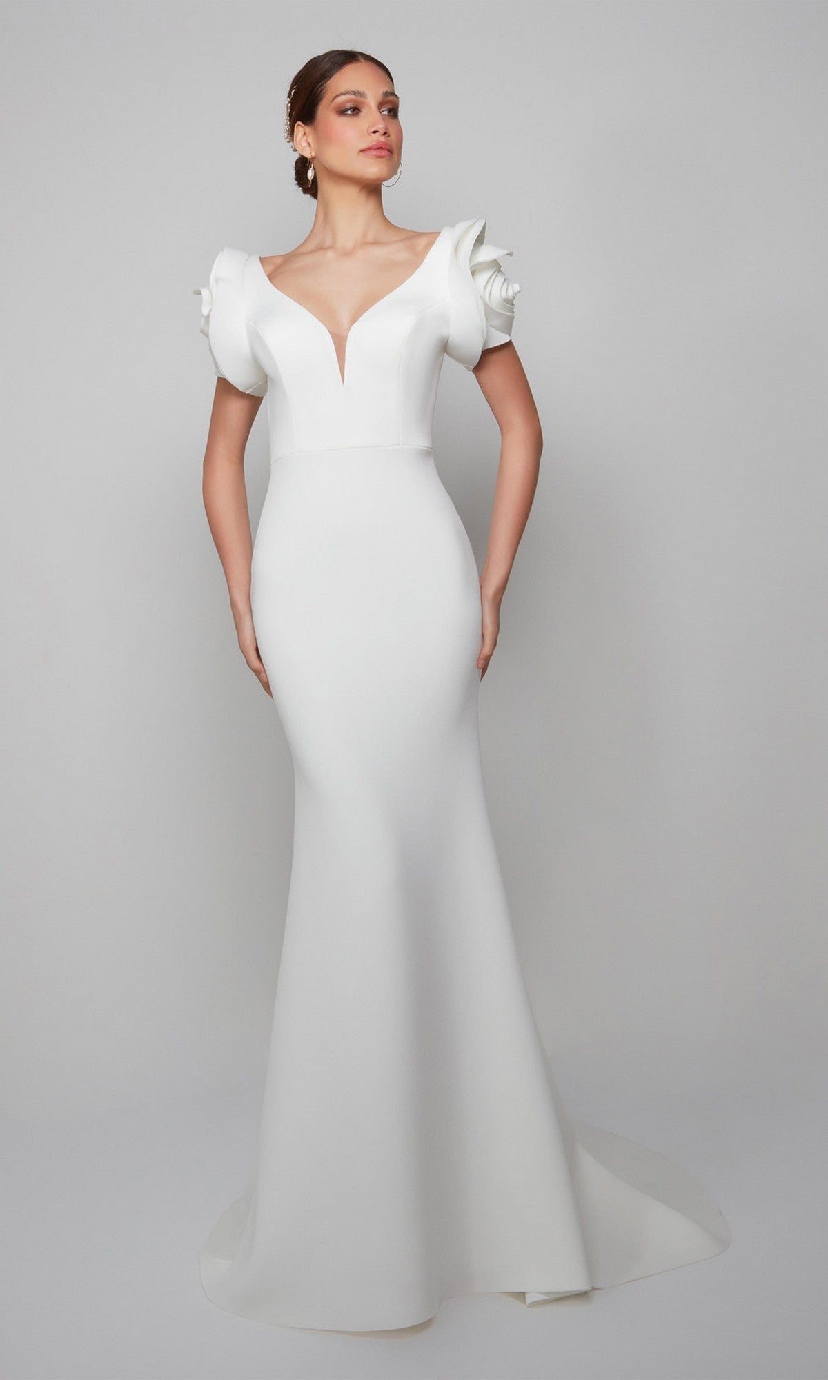 A woman models the Alyce 7066 long formal dress, showcasing its mermaid silhouette, deep V neckline, and structured ruffled short sleeves against a plain light gray background.